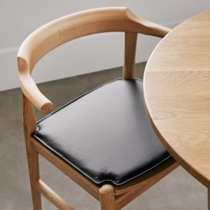 tuck in dining chair with black cushion, stained oak